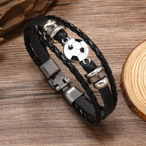 Men's multilayer braided leather bracelet with soccer charm on dark wood background