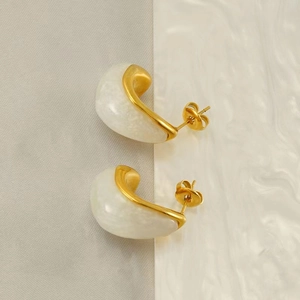 Détail de boucles d'oreilles en C plaquées or 18K avec résine marbrée sur tissu texturé