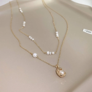 Detail of double-layer gold-plated necklace with elegant pearls and baroque pendant