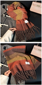 Detail shot of a warm wool scarf with orange stripes and fringe on a grey coat
