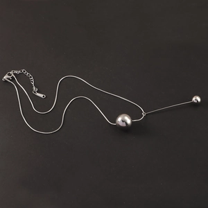 Detail of silver stainless steel snake chain featuring large sphere and tassel rod pendant