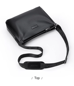 Detail view of black lychee grain leather shoulder bag with embossed logo and wide strap