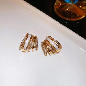 Detailed close-up of gold-plated fan-shaped earrings with mother of pearl and zircon