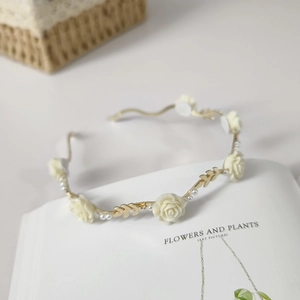 Detailed shot of golden metal headband with cream roses and pearls on an open book