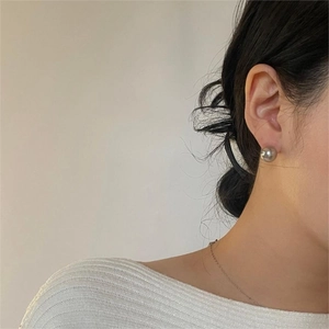 Close-up of minimalist silver-grey round pearl stud earring worn on model's ear