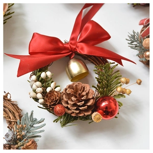 Detailed shot of Christmas mini wreath with red bow, gold bell, pine cones and green branches