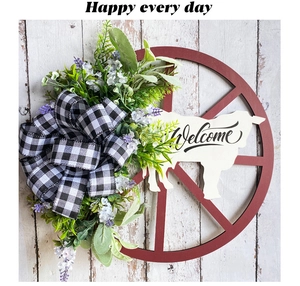 Detail of wooden wheel wreath with black and white bow, greenery and sheep welcome sign