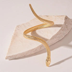 Detailed view of a golden spiral snake arm cuff with bionic scales on white stone
