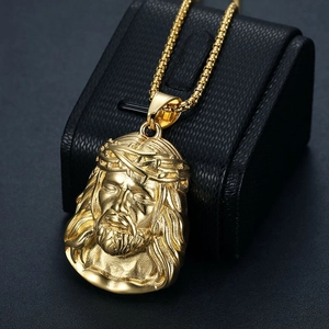 Detailed close-up of gold plated Jesus pendant with thorny crown on black leather box
