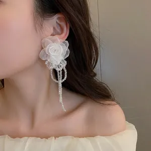 Detail of white tulle flower earrings with elegant translucent beaded long tassels