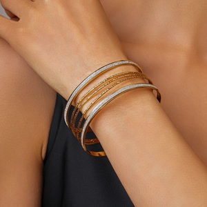 Detail of layered geometric metal bracelets with gold and silver glitter textures