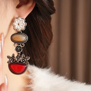 Close-up of vintage floral drop earrings with white enamel and amber stone on model