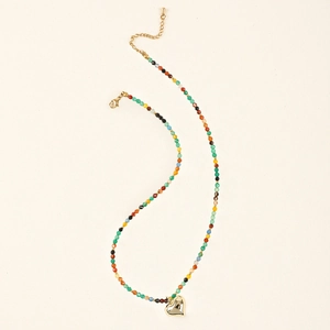Macro detail of Bohemian beaded necklace with colorful natural stones and golden heart pendant
