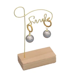 Elegant gold titanium steel hoop earrings with large grey pearls on a smile display stand