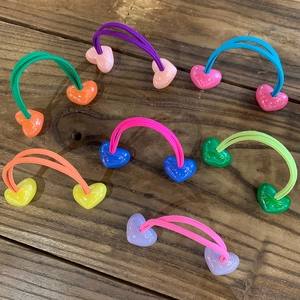 Set of colorful candy-colored elastic hair ties with heart-shaped beads on wood background