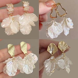 Detail view of shell flower earrings with pearlescent petals and gold-plated hardware