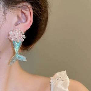 Detail of pink pearl bead earrings with an iridescent mermaid tail worn by a model