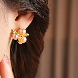 Detail of vintage gold branch earrings with champagne pearls on model