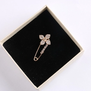 Detailed top view of a gold swan brooch with rhinestones on a black velvet pad