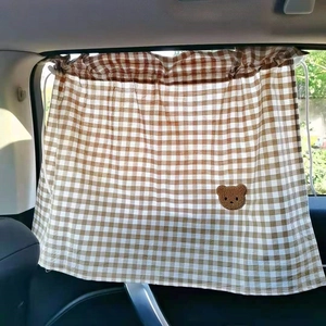 Detail of brown plaid car sunshade with cute 3D bear embroidery and drawstring
