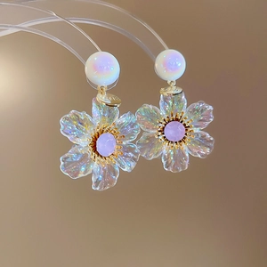 Macro shot of floral resin earrings with iridescent petals and purple gemstone center