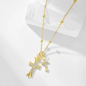 Macro shot of gold double cross pendants with cubic zirconia on white stone background