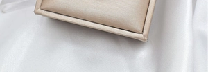 Close-up of a premium champagne gold satin jewelry box on white silk background