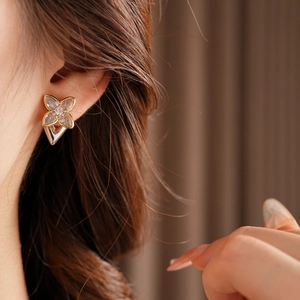 Close-up of sparkling zircon clover stud earrings worn to show elegant jewelry detail