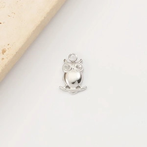 Close-up of a silver stainless steel owl pendant with inlaid eyes on a stone base
