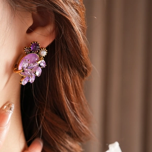 Close-up of a model wearing purple crystal flower earrings with zircon and pearl details