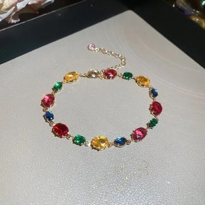 Macro detail of French style gold bracelet featuring multi-color oval cut zircons and clasp
