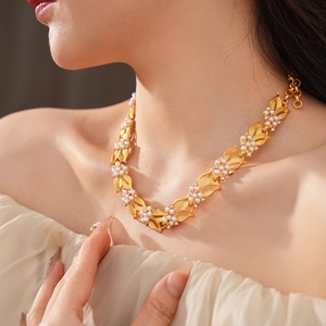 Detail of vintage gold leaf necklace with pearls and zircon stones on a model