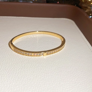 Détail d'un bracelet jonc doré orné de deux rangées de zircons brillants et fermoir