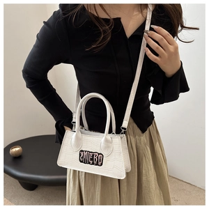 Detail of white crocodile texture crossbody bag with AMIEBO patch on model