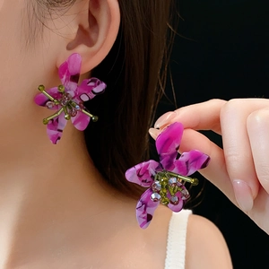 Detail of purple flower earrings with marble texture petals and handmade beaded center