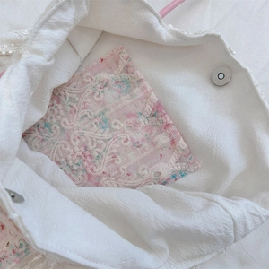 Detail of canvas bag featuring floral lace inner pocket and magnetic metal closure