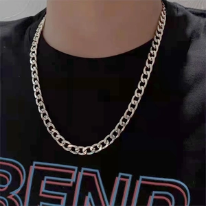 Close-up of a chunky silver Cuban link chain necklace worn on a black t-shirt