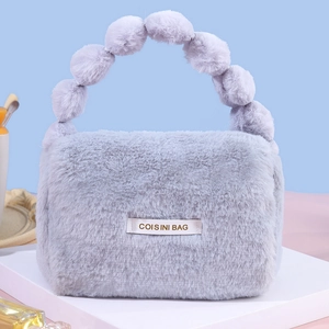 Chic grey plush handbag with fluffy faux fur ball handle and stylish brand patch