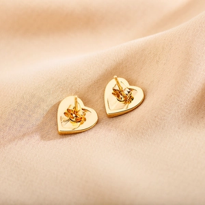 Macro view showing the butterfly clasp and pin detail of the gold heart stud earrings