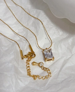 Close-up of gold chain necklace with rectangular emerald zircon and adjustable extender