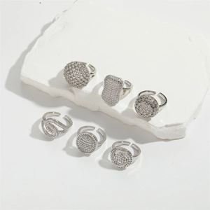 Detail of silver geometric micro-inlaid zircon open rings on white stone platform