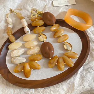 Retro chunky acrylic jewelry set with amber resin necklaces and orange bangle on wooden tray