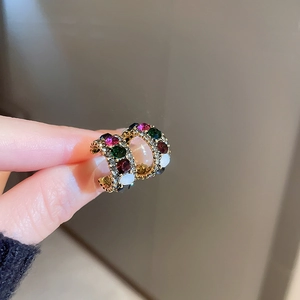 Macro shot of gold hoop earrings with colorful set gemstones being held by hand