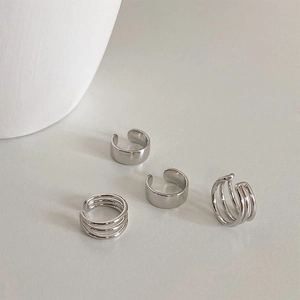Detail of four silver cuff earrings with minimalist polished and multi-layered band designs