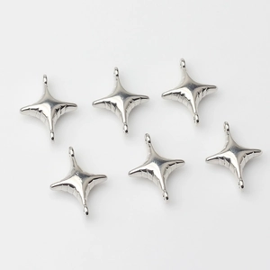 Close-up of six silver star-shaped jewelry pendants with a polished metallic finish