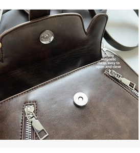 Detail of strong magnetic closure and metal zippers on a retro brown leather saddle bag