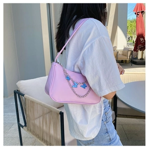 Pink crescent shoulder bag with silver chain and blue butterfly charms worn by model
