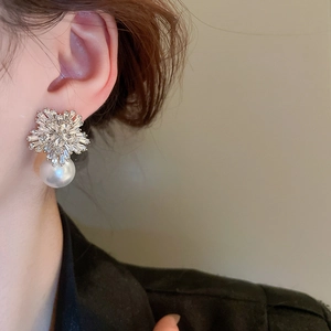 Detail of silver stud earring with flower-shaped crystals and a large white pearl drop