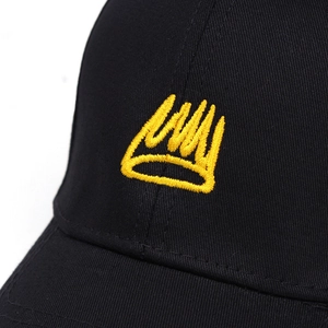 Close-up of yellow 3D crown embroidery on a premium black cotton baseball cap