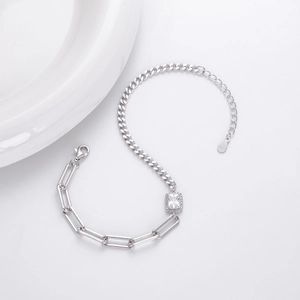 Detail of S925 hallmark tag on silver paperclip and cuban link chain bracelet with zircon